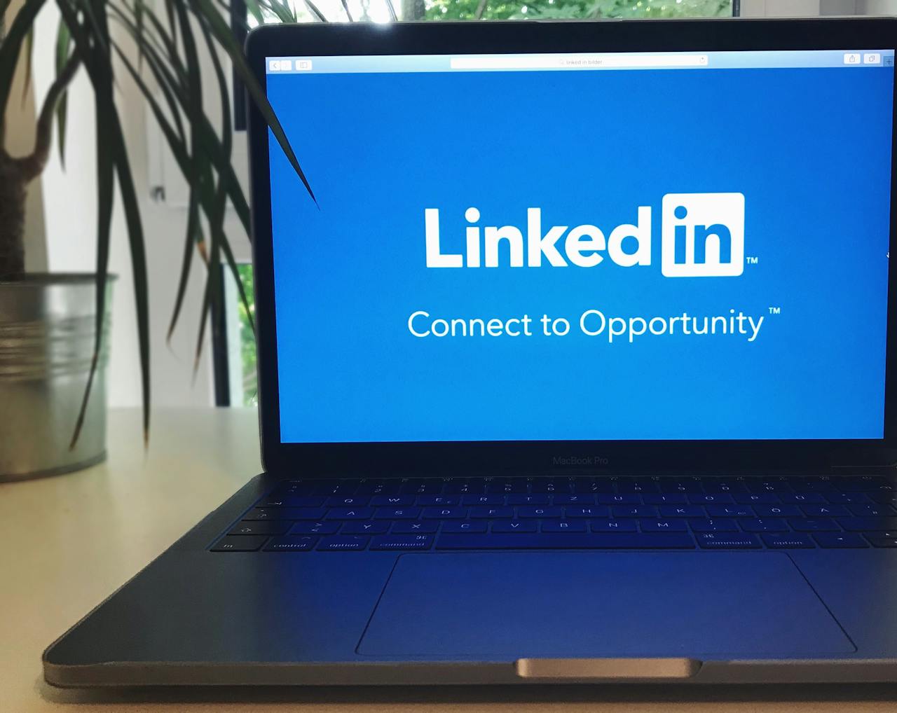 A laptop screen displaying the LinkedIn logo with the text Connect to Opportunity.